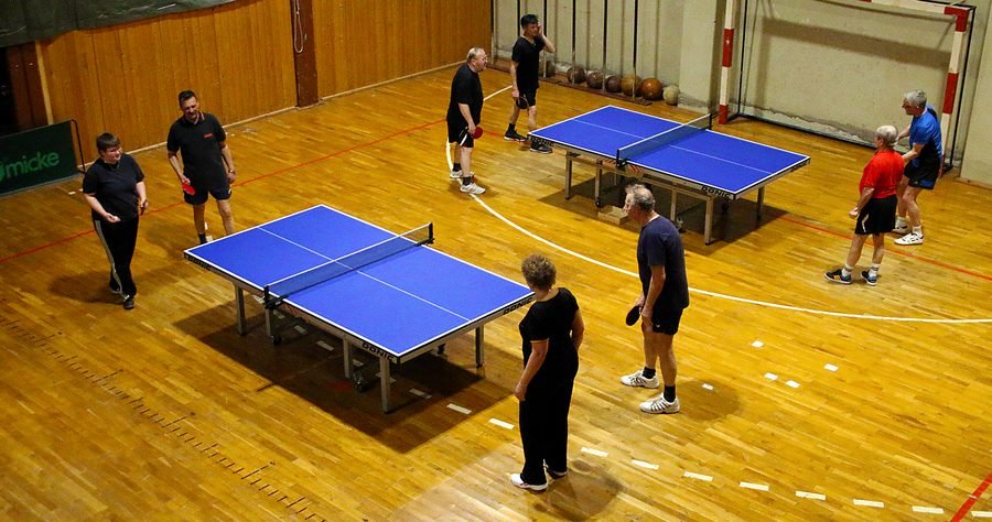 Mehrere Tischtennisplatten in der Turnhalle, an allen wird gespielt.